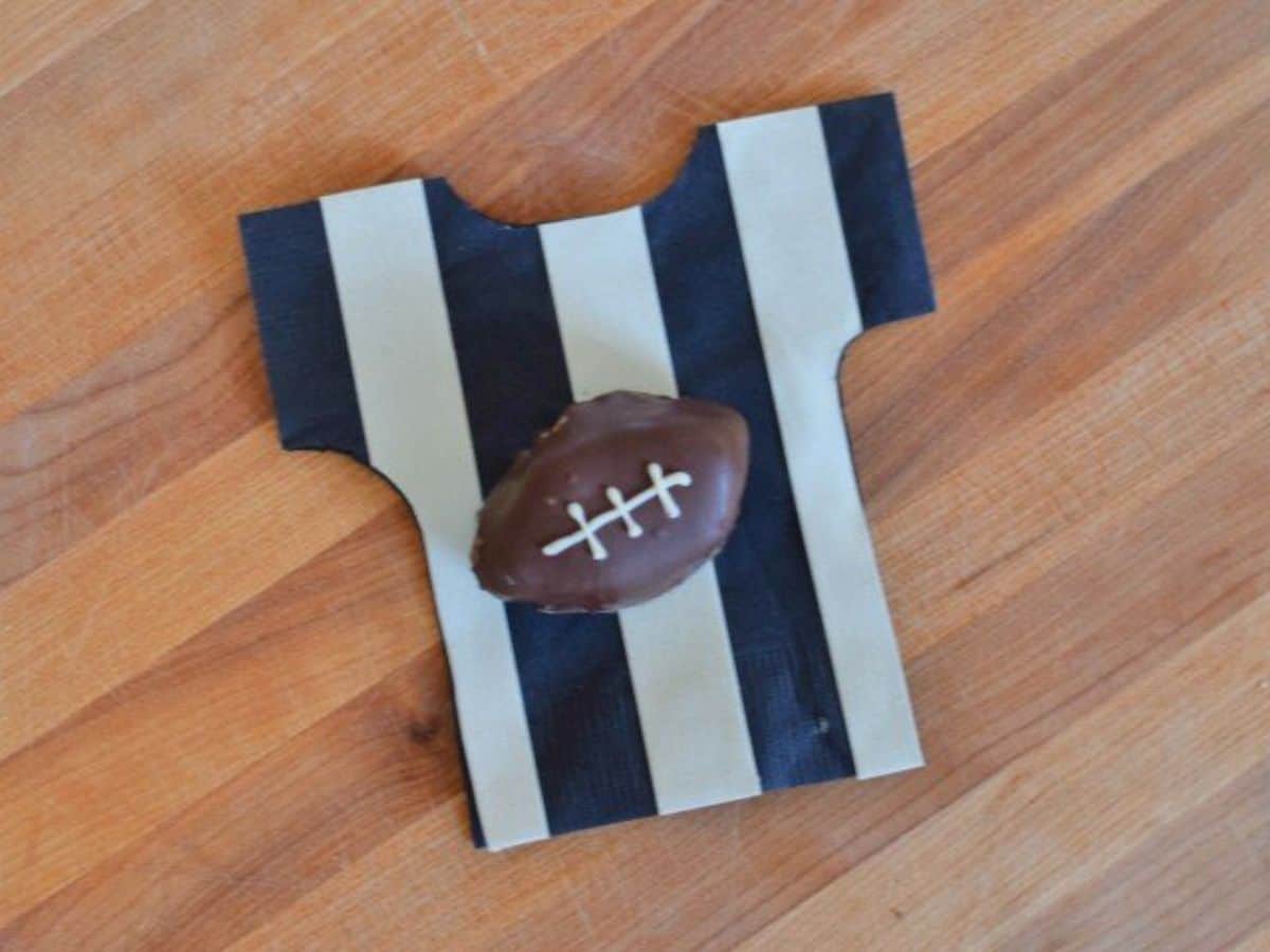 Image shows an overhead view of a football shaped oreo cookie ball on a referee striped napkin.