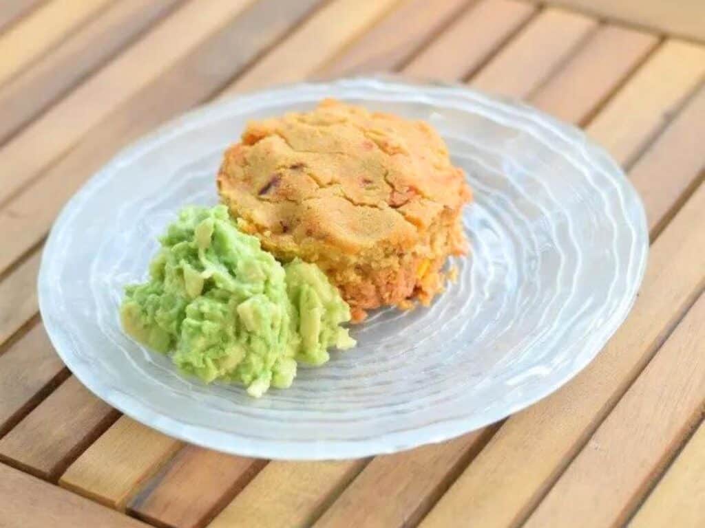 Image shows tamale pot pie with guacamole on a plate,