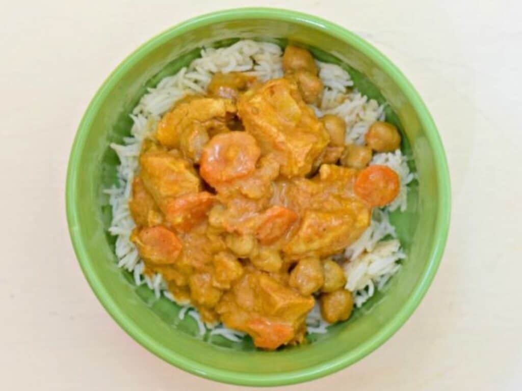Image shows yummy chicken tikka masala on top of rice in a bowl.