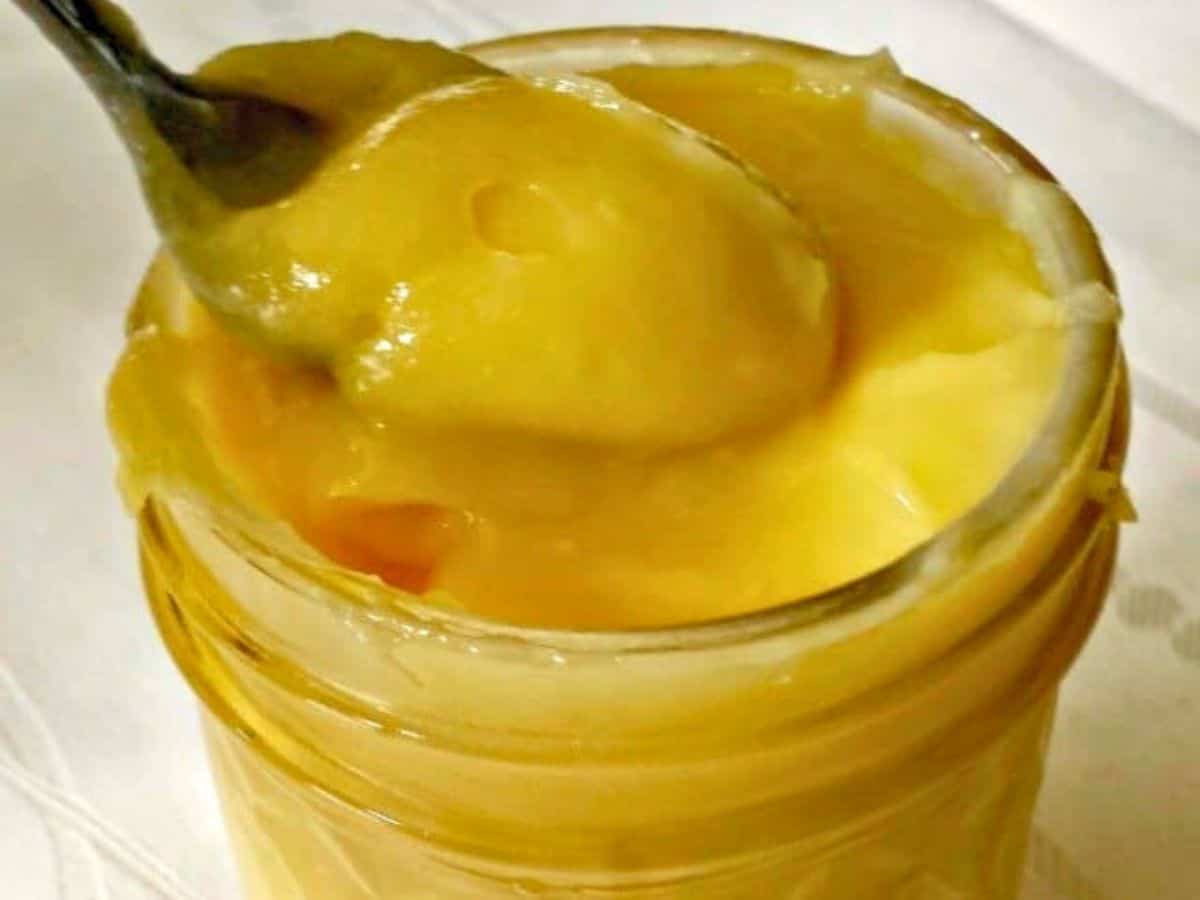 Image shows a spoon dipping into a jar of Lemon Curd.