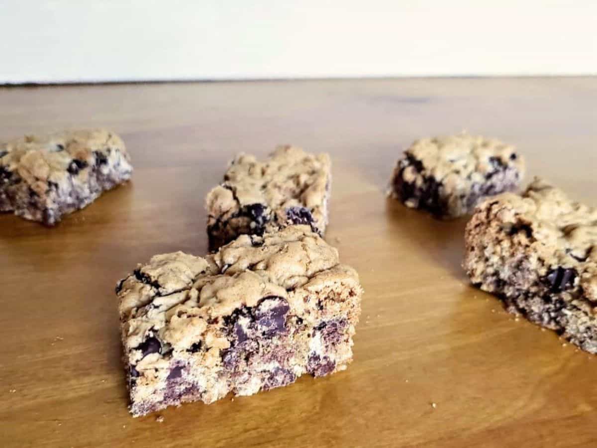 Image shows A group of chocolate chip oat bars on a wooden table.