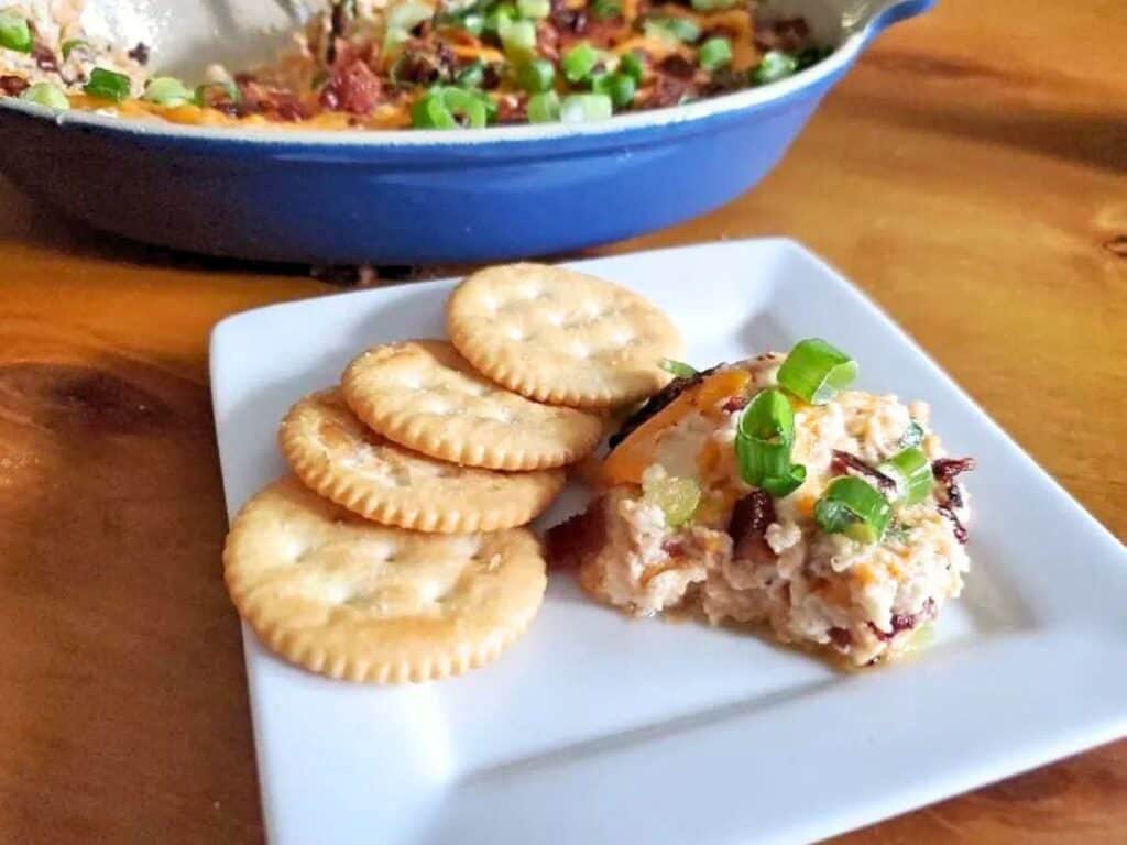 Image shows irresistible hot bacon cheddar on a plate with crackers.