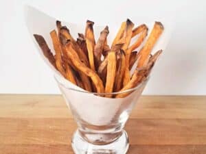 Image shows sweet potato fries in a glass.