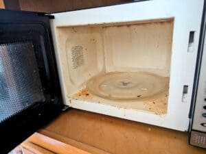 Image shows a Filthy microwave with the door open.