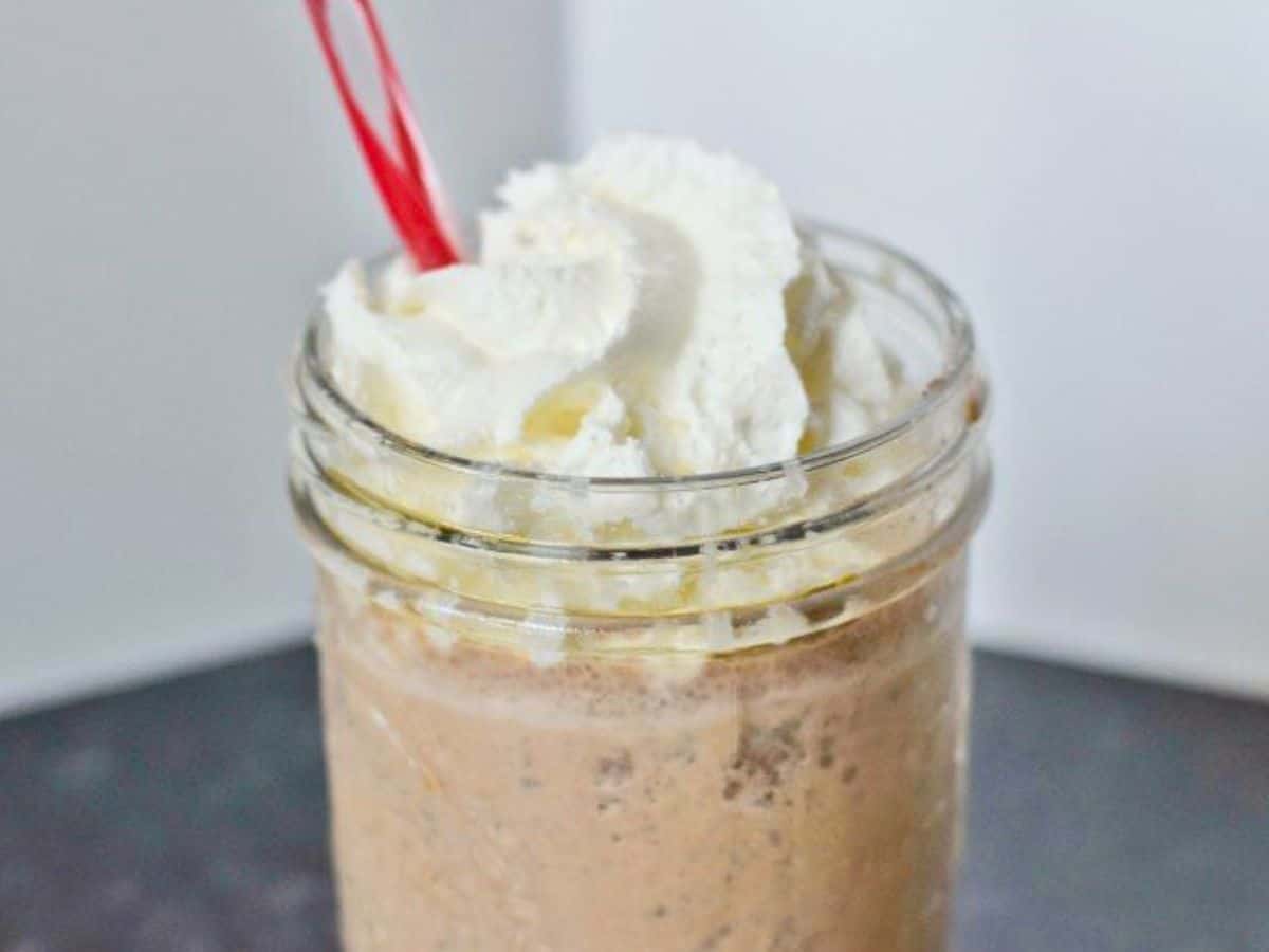 Image shows a closeup of a Copycat Java Chip Frappuccino in a mason jar with whipped cream and a straw.