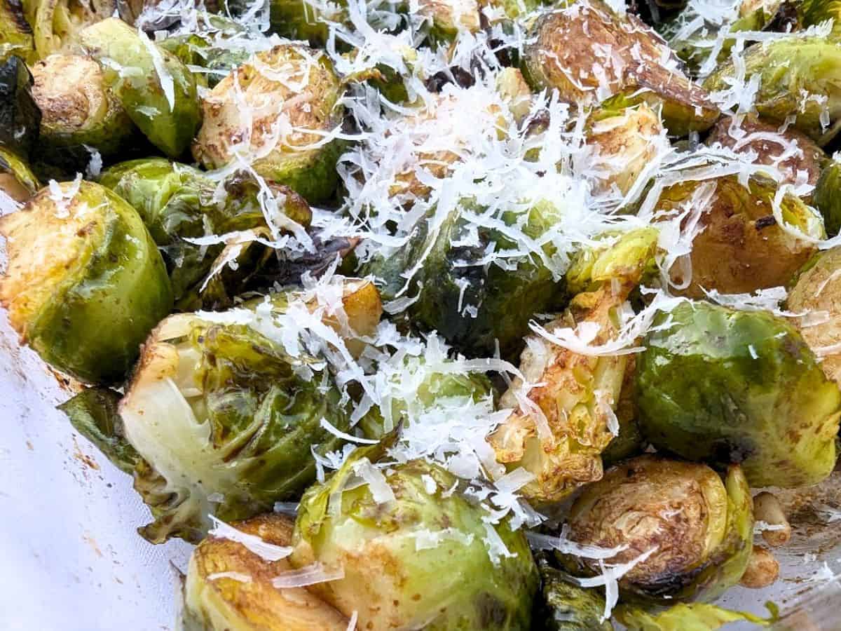 Image shows sliced roasted Brussels sprouts topped with grated Parmesan cheese.