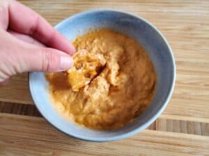 Image shows pretzel dip into buffalo chicken dip in a bowl.