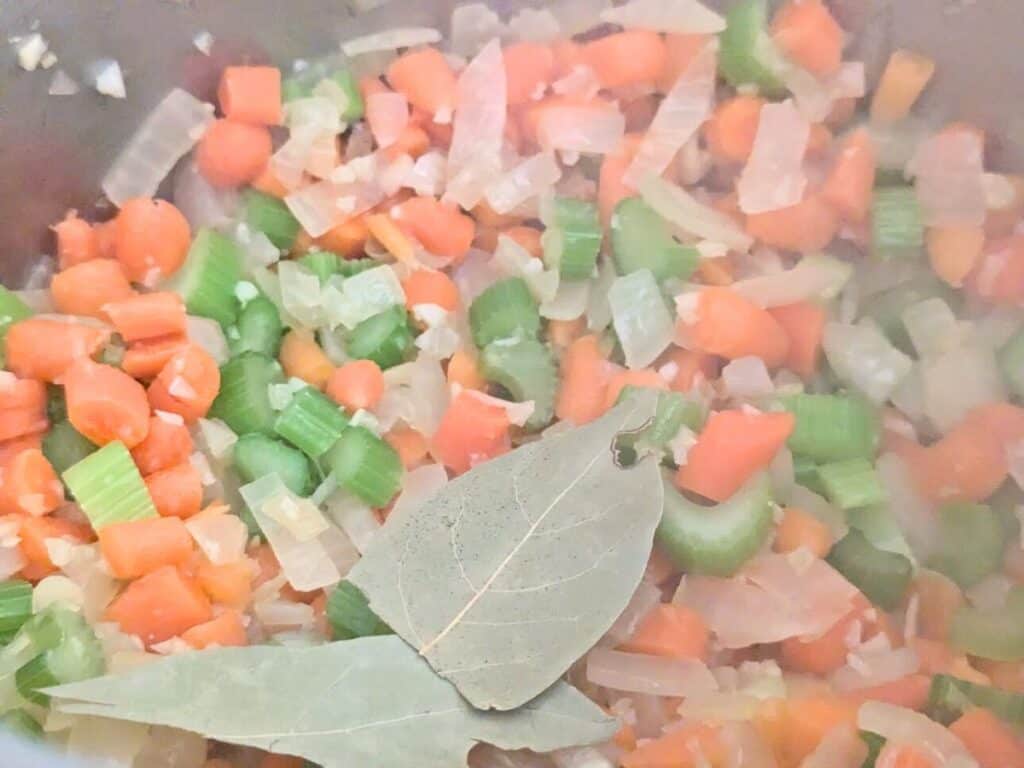 Image shows vegetables for Instant Pot chicken noodle soup mixed together with bay leaves.