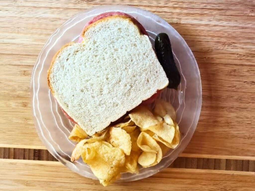 Image shows plated delicious sandwich bread with chips.