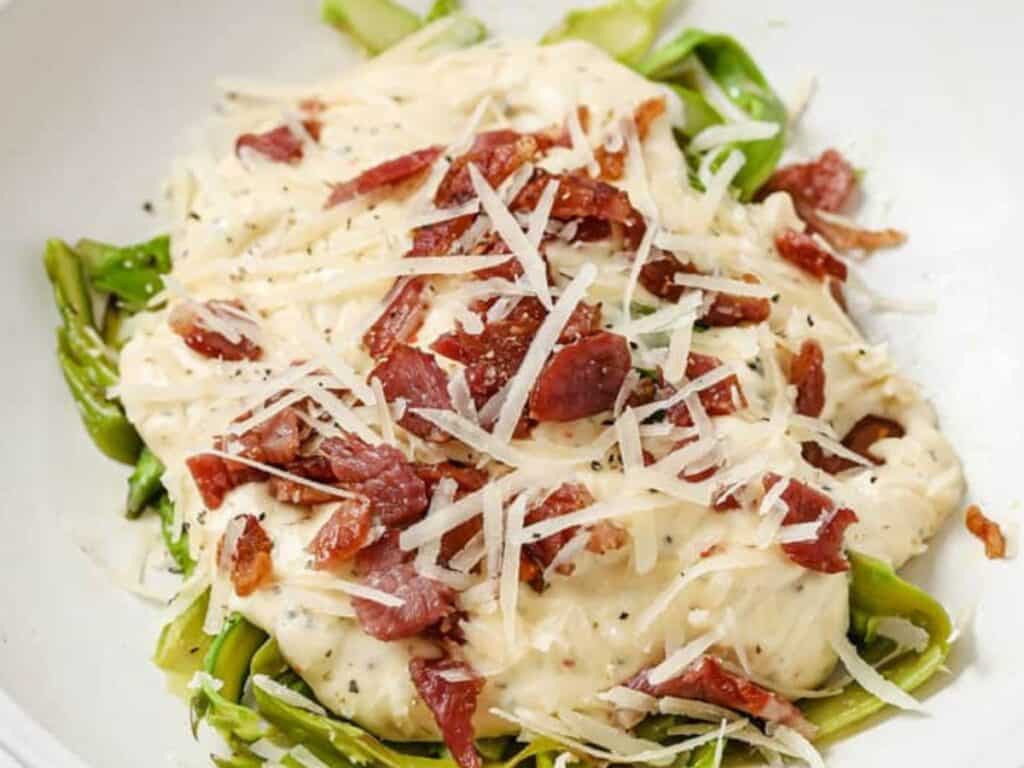 Image shows asparagus noodles with alfredo sauce and bacon recipe.