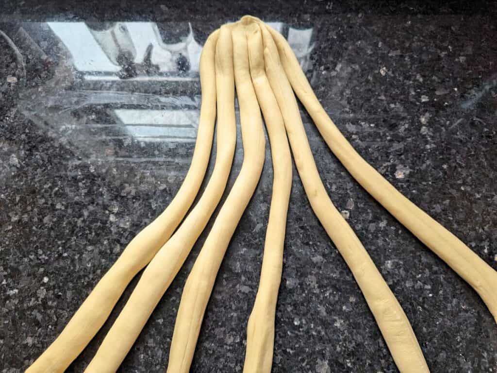Image shows challah dough divided into six equal pieces for braiding.