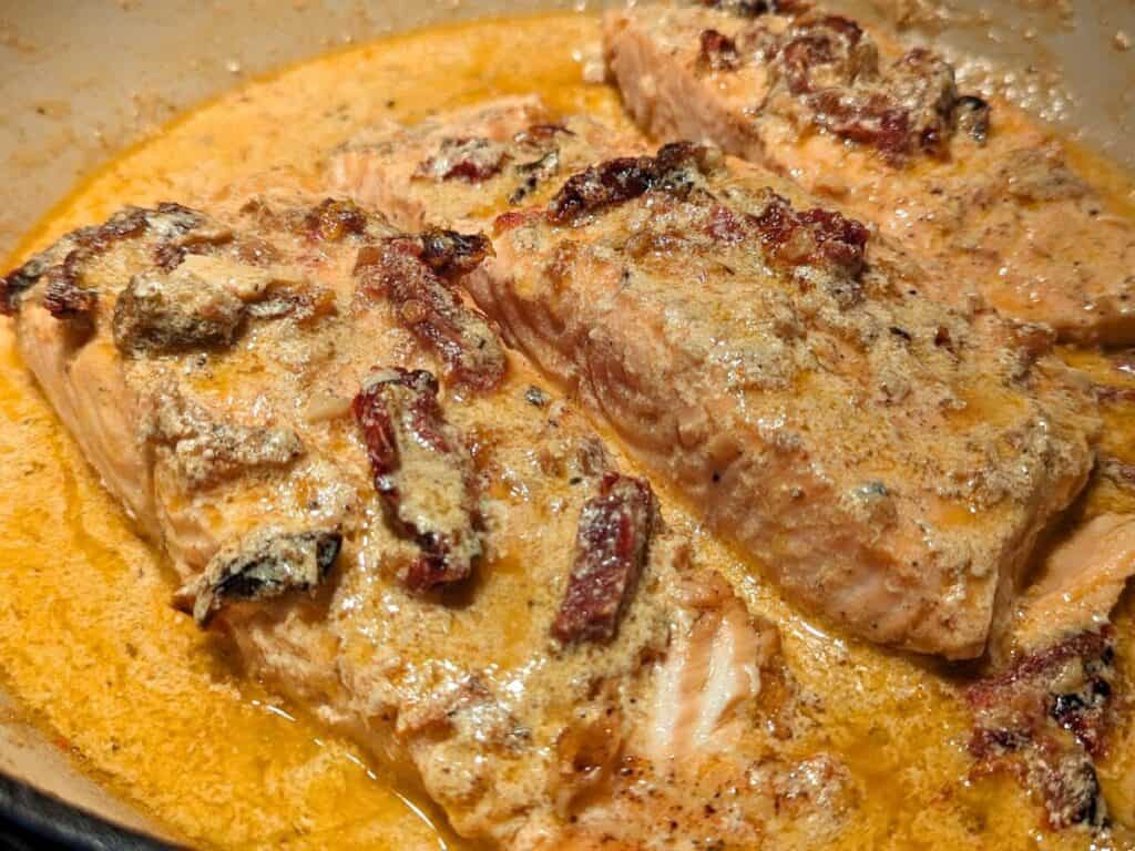Image shows cooked and ready to serve creamy sun-dried tomato salmon.