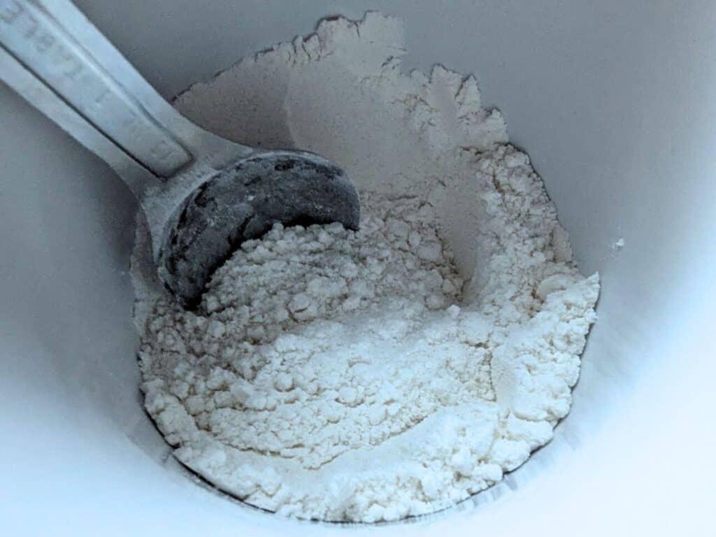 Image shows flour, sugar, baking powder, and salt combined in a microwave-safe mug.