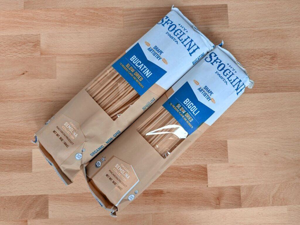Image shows Two unopened packs of Sfoglini pasta.