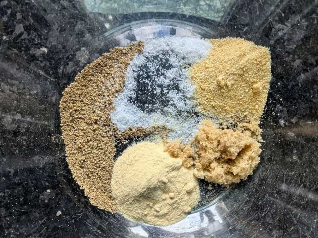 Image shows glass bowl with salt, pepper, onion powder, garlic powder, chili powder, and brown sugar mixed together.