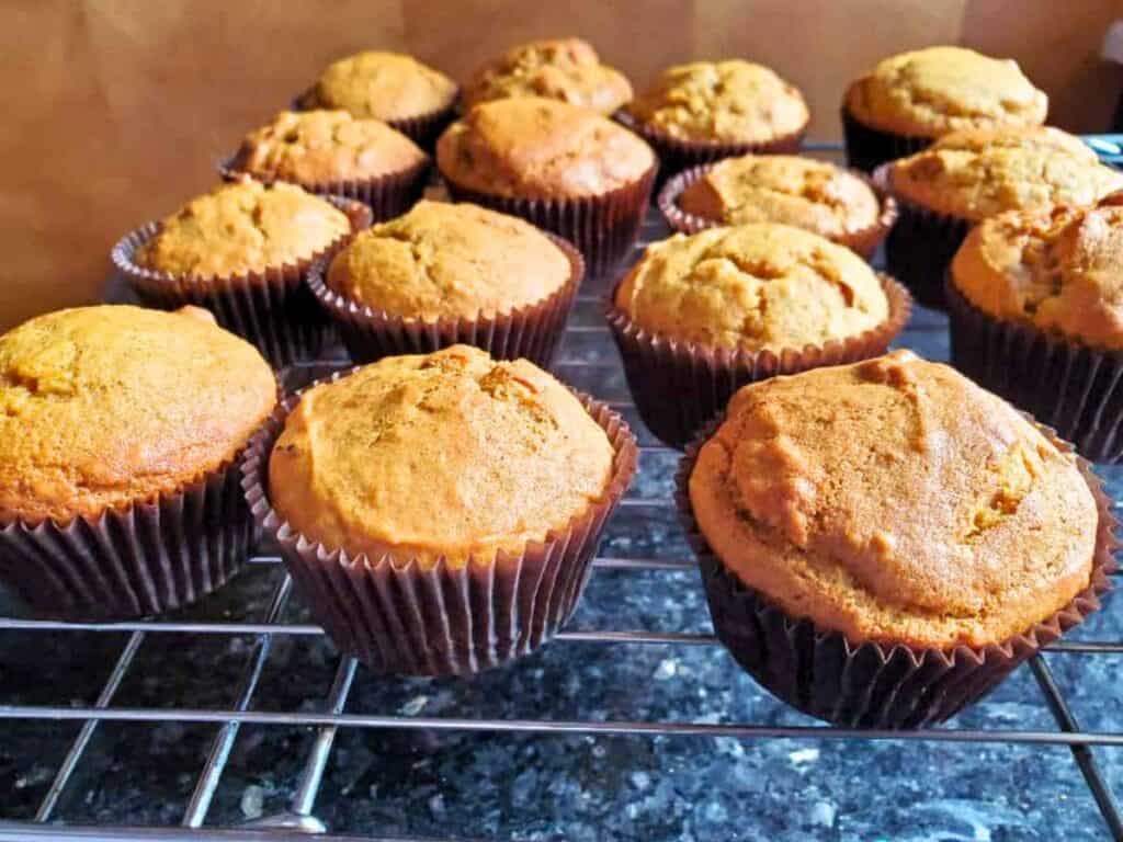 Image shows cranberry pumpkin muffins on a cooling rack.