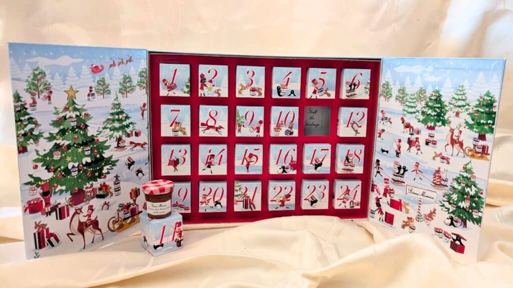An Advent calendar with numbered doors and festive illustrations, opened to reveal small jars of Bonne Maman preserves inside&mdash;a delightful twist on traditional Advent calendars.