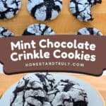 Mint chocolate crinkle cookies with a powdered sugar coating are arranged on a wooden surface, some whole and one partially eaten, with more cookies displayed on a plate below.