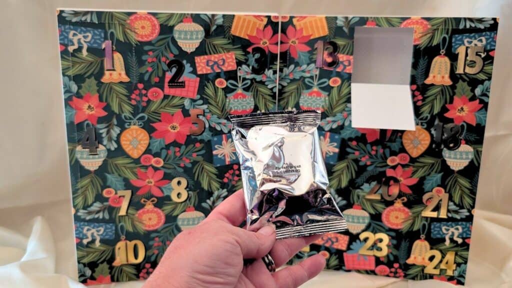 A hand holding a silver package, reminiscent of the treats found in Advent calendars.