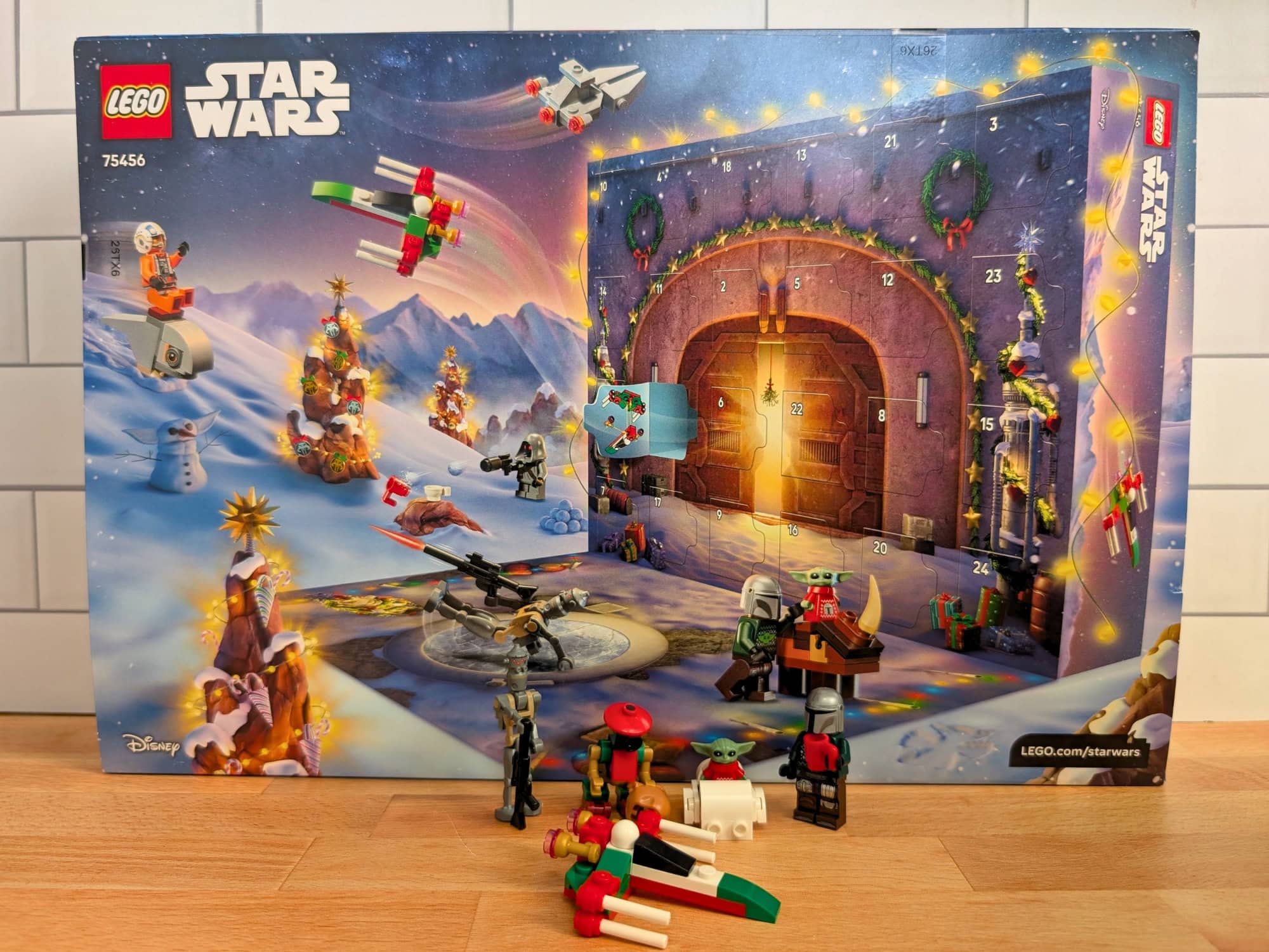 LEGO Star Wars advent calendar box set with holiday-themed mini-figures and a small vehicle on a wooden surface.