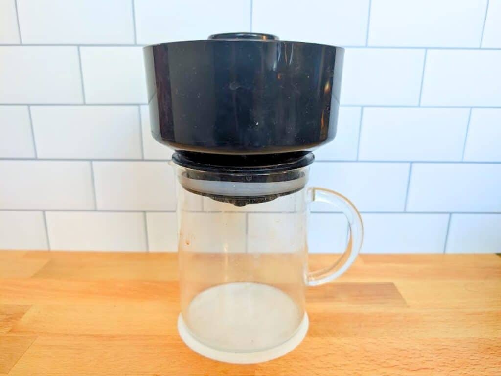A black plastic coffee dripper sitting on top of a clear glass carafe.
