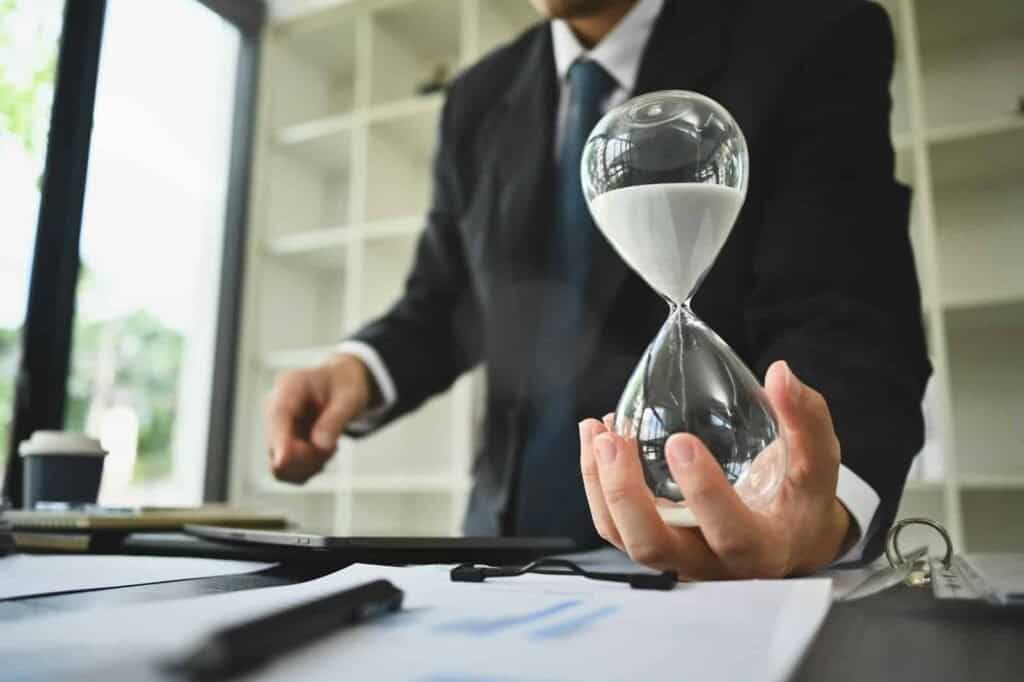 Hånd af forretningsmand, der holder timeglas.