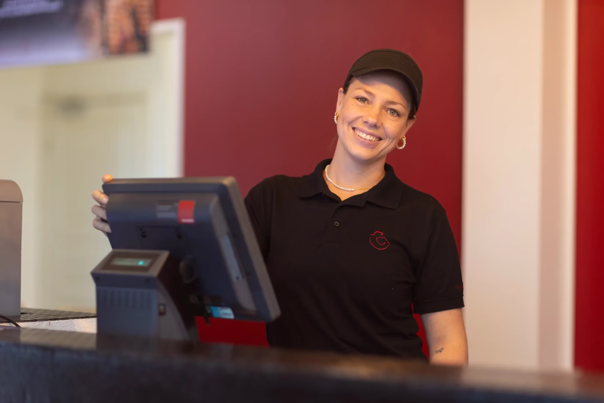 Smilende kvindelig Kylling & Co medarbejder ved kassen, klar til at yde service