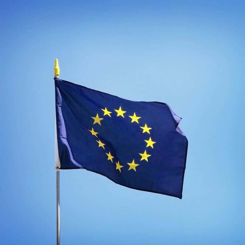 EU-flag flyver højt med blå himmel i baggrunden, symbol på europæisk samarbejde og frihed.