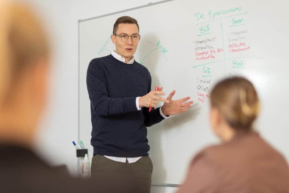 1. Mænd underviser i præsentationsteknik foran hvid tavle i et klasseværelse.