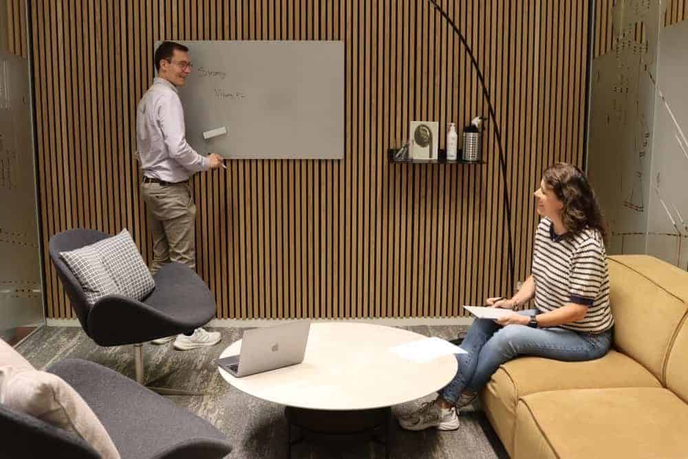 Moderne kontormøde med to personer, der deltager i en brainstorming session i et stilfuldt mødelokale.
