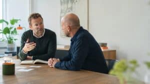 To mænd i samtale under strategisk rådgivning i et moderne kontormiljø.