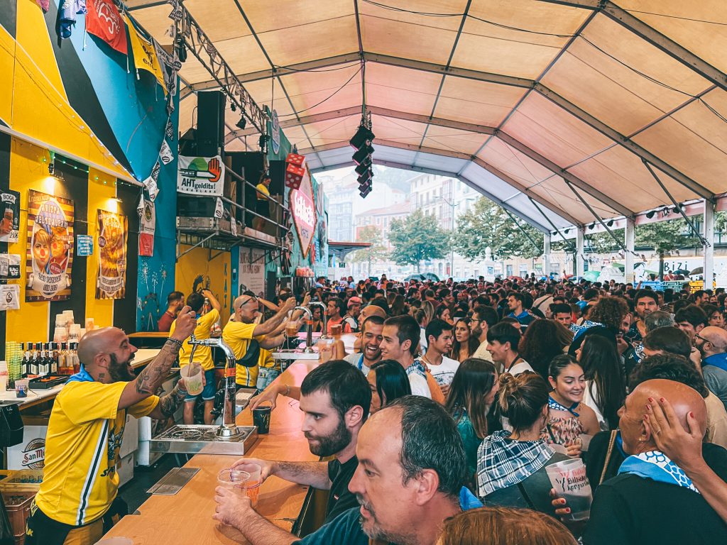 Crowds of people at the bar inside a tent in the main arena of La Semana Grande