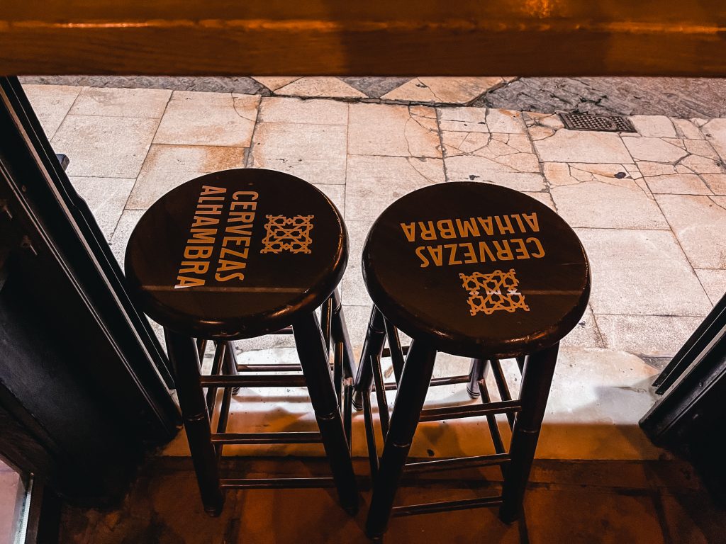 Cervezas Alhambra branded bar stools in the window of Munich bar in Alicante