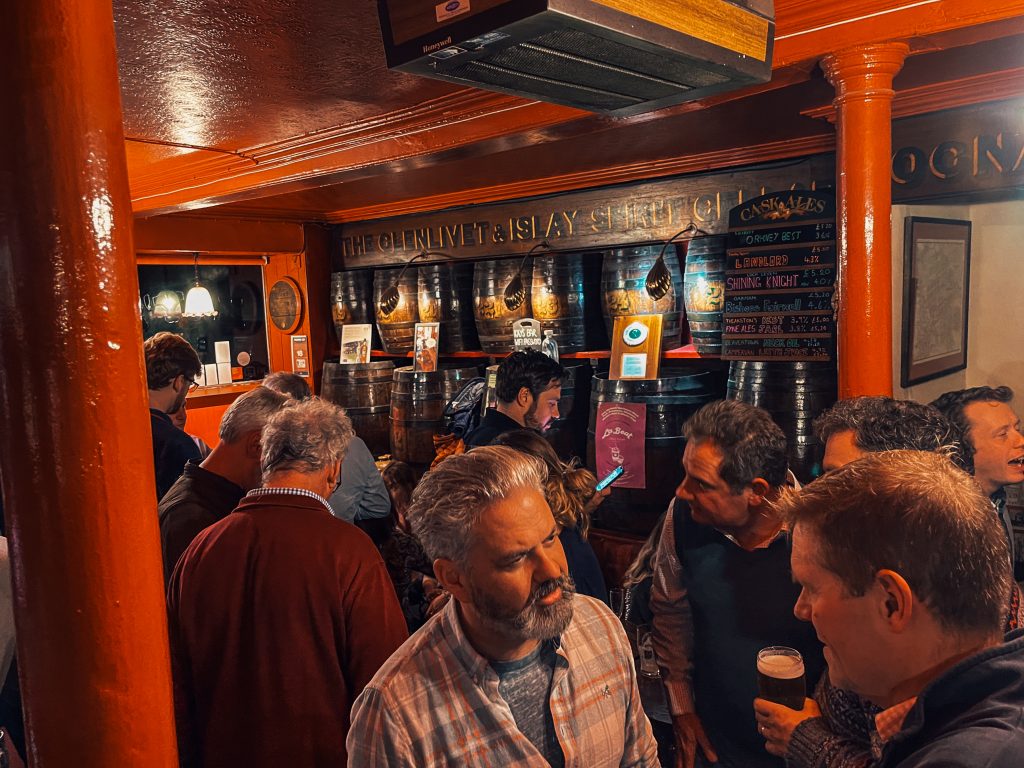 The busy interior of Kays Bar in Edinburgh, with decorative wooden casks and old signage