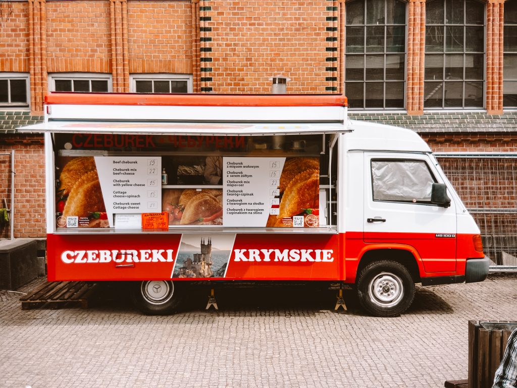 An 80's looking van is parked on a cobbled surface selling Ukrainian chebureki from the kitchen in the back.
