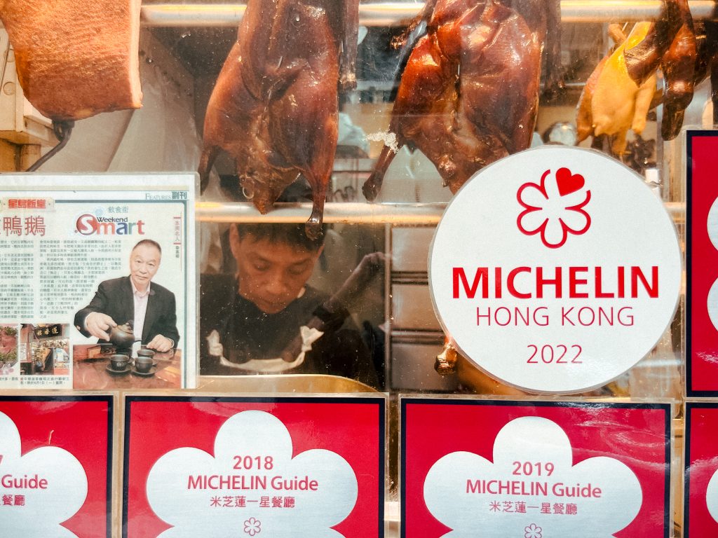 Michelin-awarded restaurant window with roasted meats and a chef working inside making some of the best food in Hong Kong.