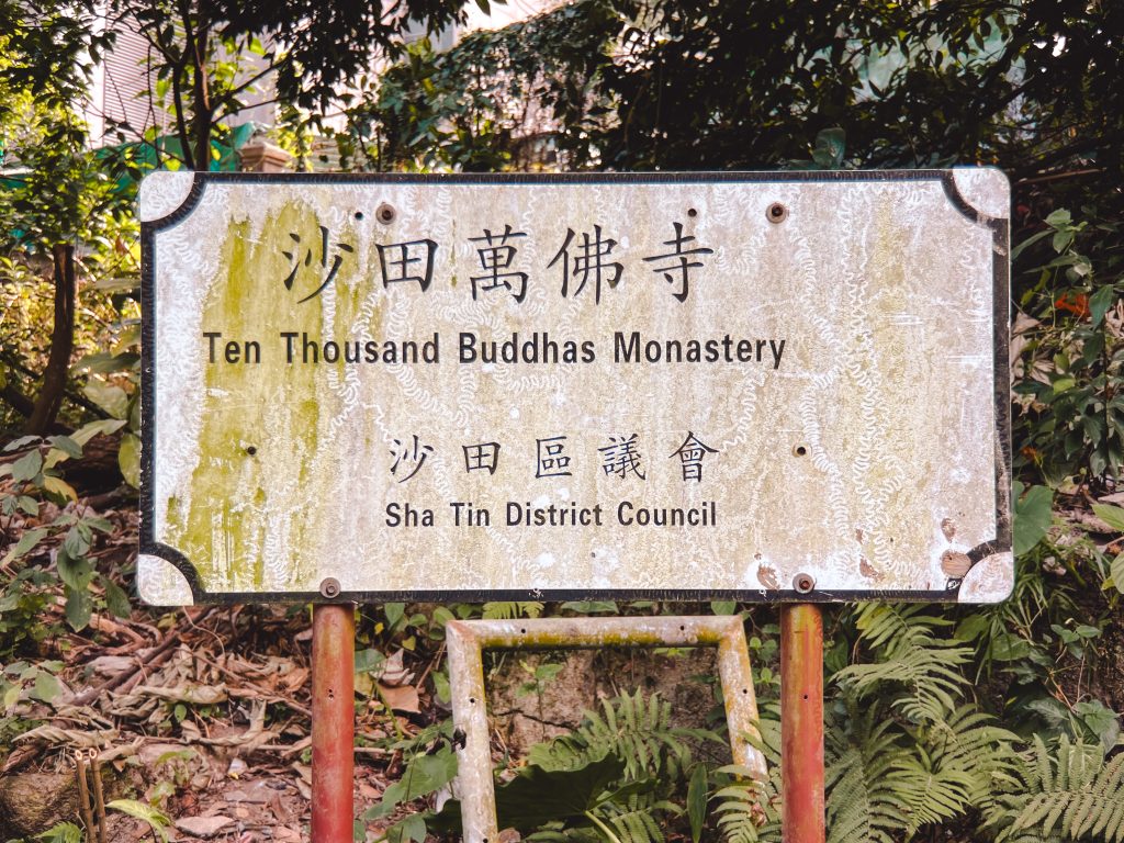 Sign for the Ten Thousand Buddhas Monastery, nestled in the Hong Kong lush greenery, shows signs of wear