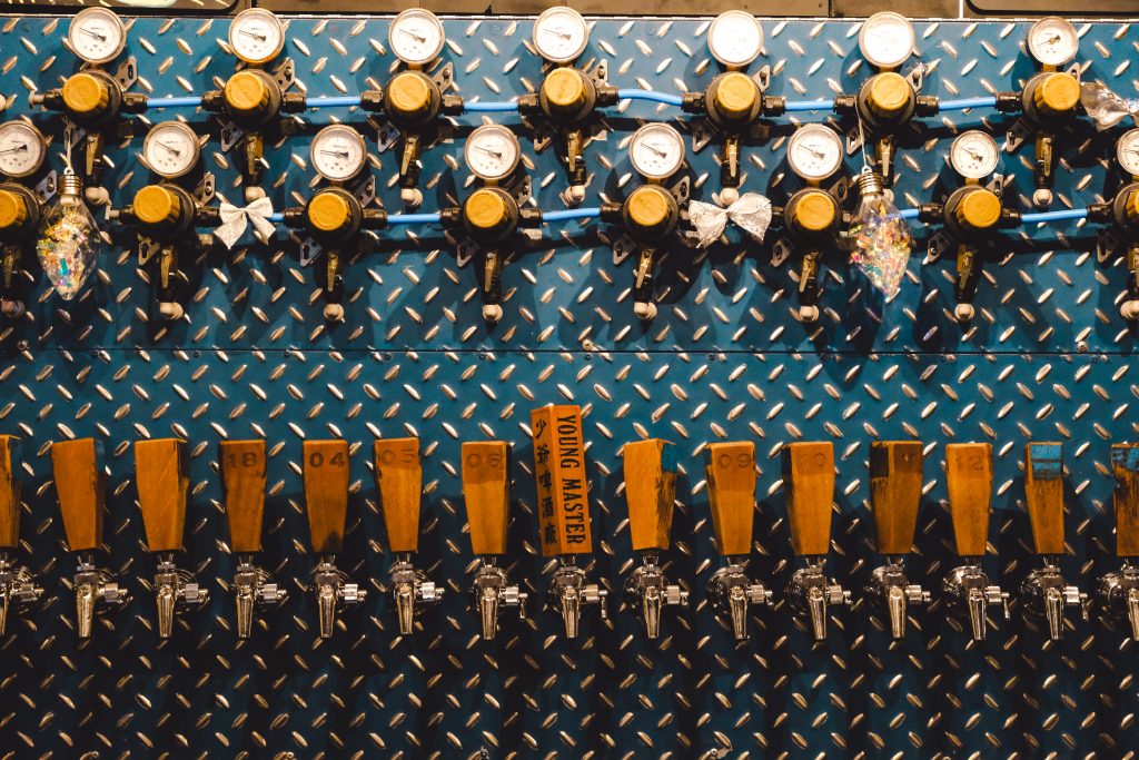 Beer taps with wooden handles attached to a midnight blue steel wall.