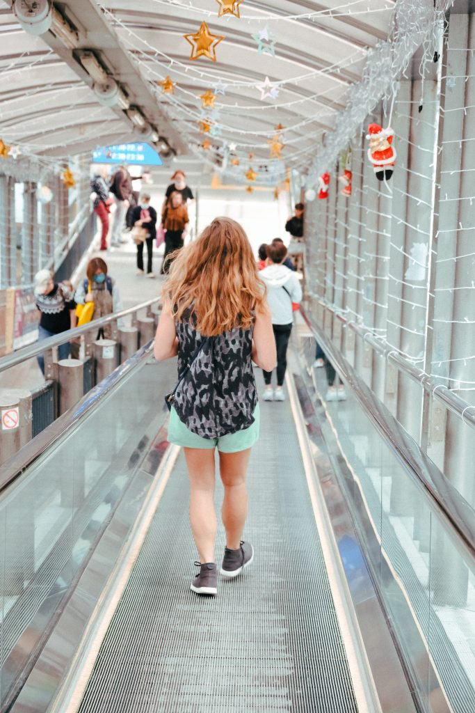Sofia walking down the Hong Kong escalator which is decorated with fairy lights and mini Santas
