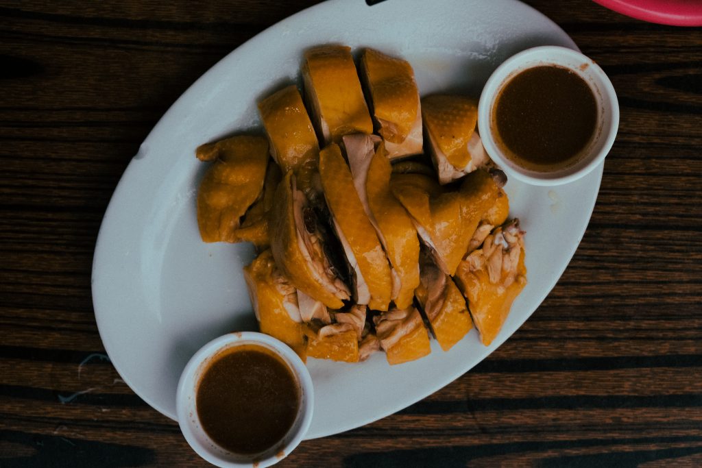 Hainese chicken on a plate accompanied by dipping sauces.
