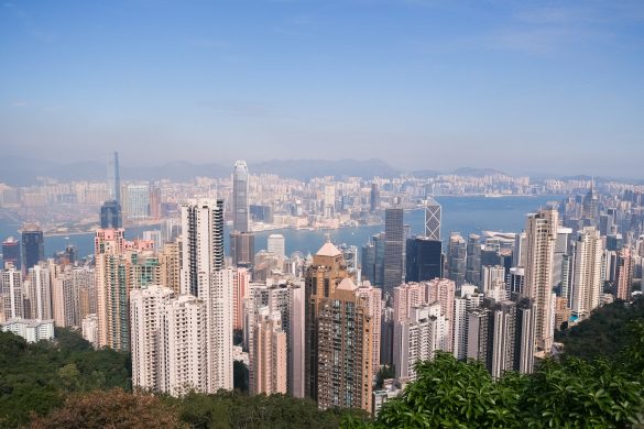 The skyline of Hong Kong dazzles with its towering skyscrapers, a shimmering bay, and distant mountains all under a clear blue sky—a perfect backdrop for an unforgettable weekend.