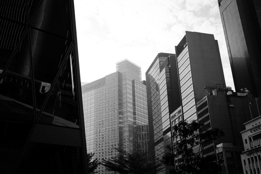 Black and white cityscape of Hong Kong with tall skyscrapers under a cloudy sky.