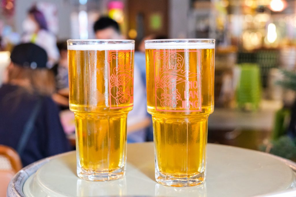Two pints of golden craft beer with Chinese style logo reading Ho Lan Jeng