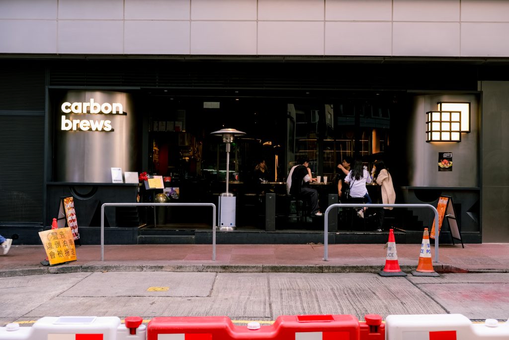 Street view of Carbon Brews in Hong Kong, with patrons sitting by the window, drinking craft beer