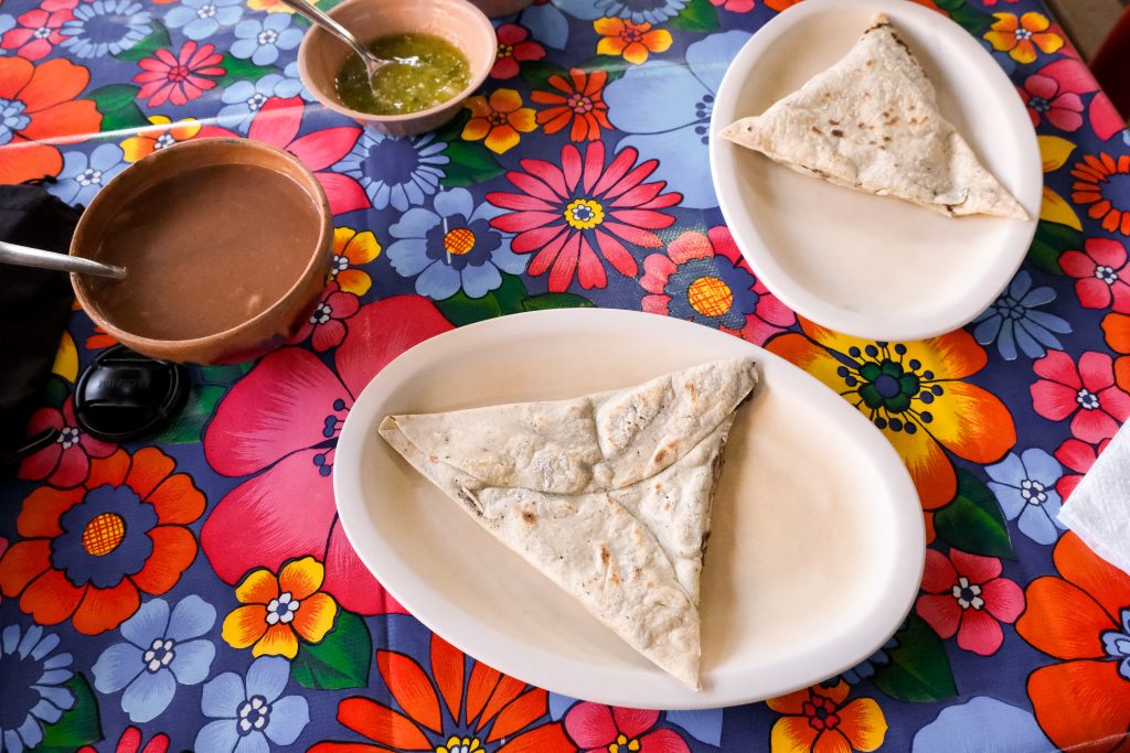 Tetelas, dipping sauces, on a brightly coloured table cloth.