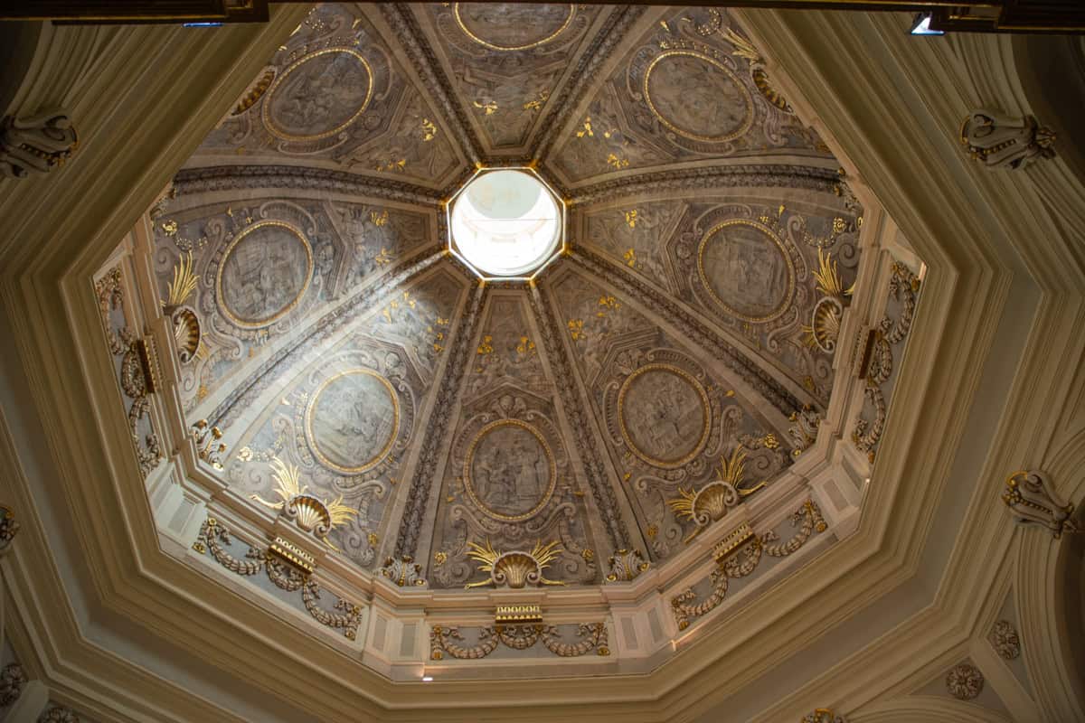 Elegant ornate ceiling inside a historic building with intricate gold detailing and frescoes.