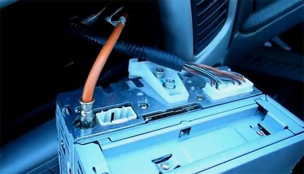 Bild eines Autoradio Adapters mit CAN-B Schnittstelle im Fahrzeug, Kabel und Stecker sichtbar.