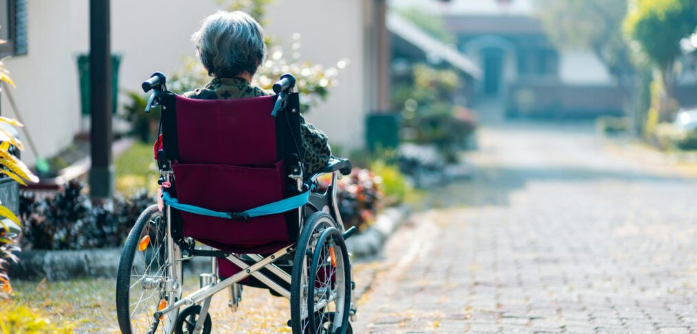 Old woman sitting in a wheelchair outside - dangers of wandering behavior in the elderly