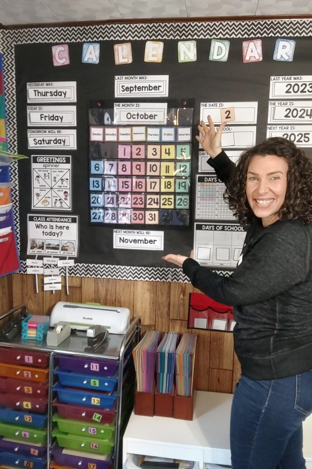 Jenn Adams by a classroom calendar, showing homeschool curriculum routines