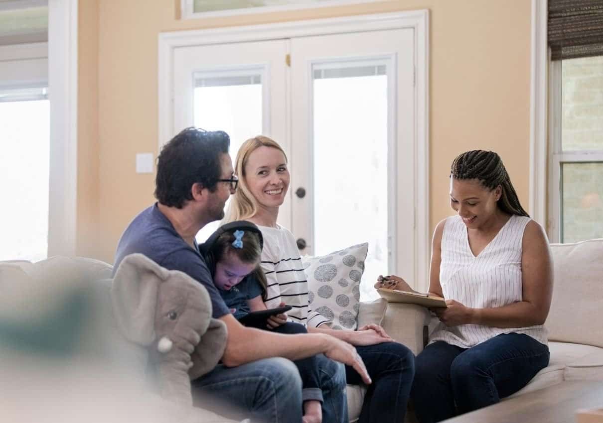 A family speaking with a smiling professional on a sofa